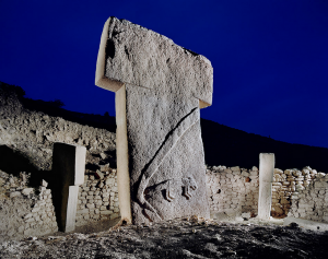 T-shaped enormous rock pillar with animal carving against night sky