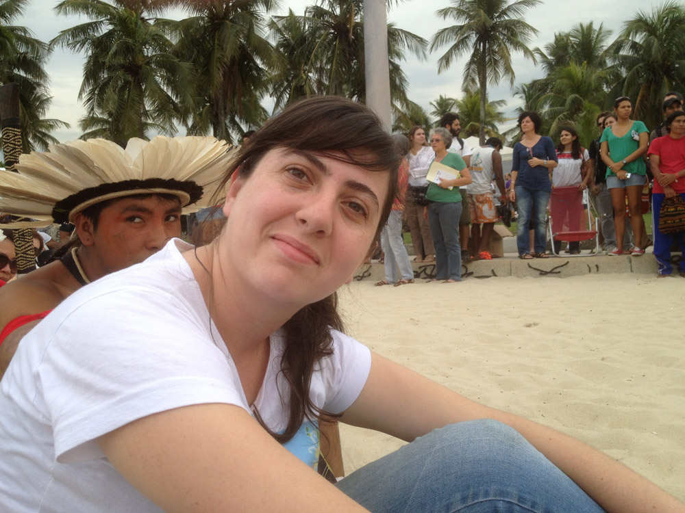 Young Brazilian woman in jeans and T-shirt in the sand, turning to smile into the camera